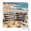 Bolsa Profe tiene mucha clase - Estampatya bolsos de playa de rayas marineras azules y blancas sobre la arena con el mar de fondo. El bolso izquierdo tiene el texto "Nuestra PROFE Marisa tiene mucha CLASE" y el derecho tiene nombres de alumnos alrededor de un corazón rosa con la frase "TE QUEREMOS".