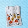 Camiseta blanca Halloween “¿Truco o trato?” doblada sobre fondo morado