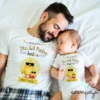 "Papá sonriente junto a su bebé, ambos con camisetas blancas personalizadas con diseño de pollito y la frase 'Nuestro primer Día del Padre juntos'."
