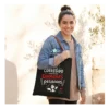 Bolsa de Tela Profe "No He Corregido los Exámenes" - Estampatya Bolsa de tela negra para profesora con frase divertida sobre corregir examenes y asas marrones, modelo la lleva puesta