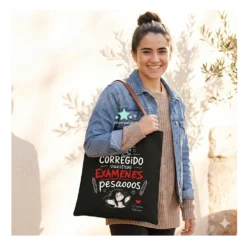 Bolsa de tela negra para profesora con frase divertida sobre corregir examenes y asas marrones, modelo la lleva puesta