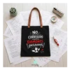 Bolsa de Tela Profe "No He Corregido los Exámenes" - Estampatya Bolsa de tela negra para profesora con frase divertida sobre corregir examenes y asas marrones, estirada sobre mesa de examenes