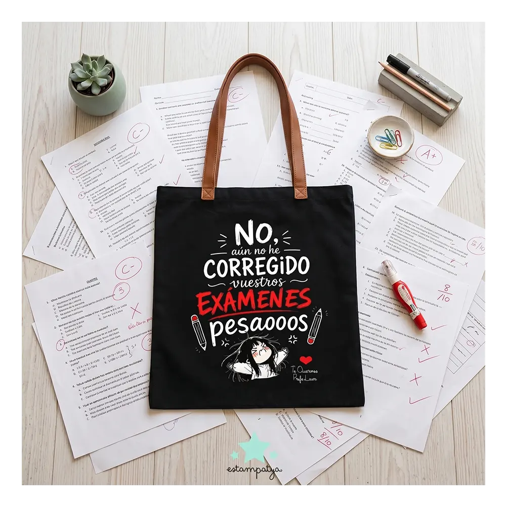 Bolsa de Tela Profe "No He Corregido los Exámenes" - Estampatya Bolsa de tela negra para profesora con frase divertida sobre corregir examenes y asas marrones, estirada sobre mesa de examenes